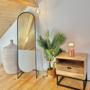A room with a wooden floor, a round mirror, a tall floor lamp, a potted plant, and a wooden side table with a globe lamp. - Porto Domus 210 Penthouse (Porto)