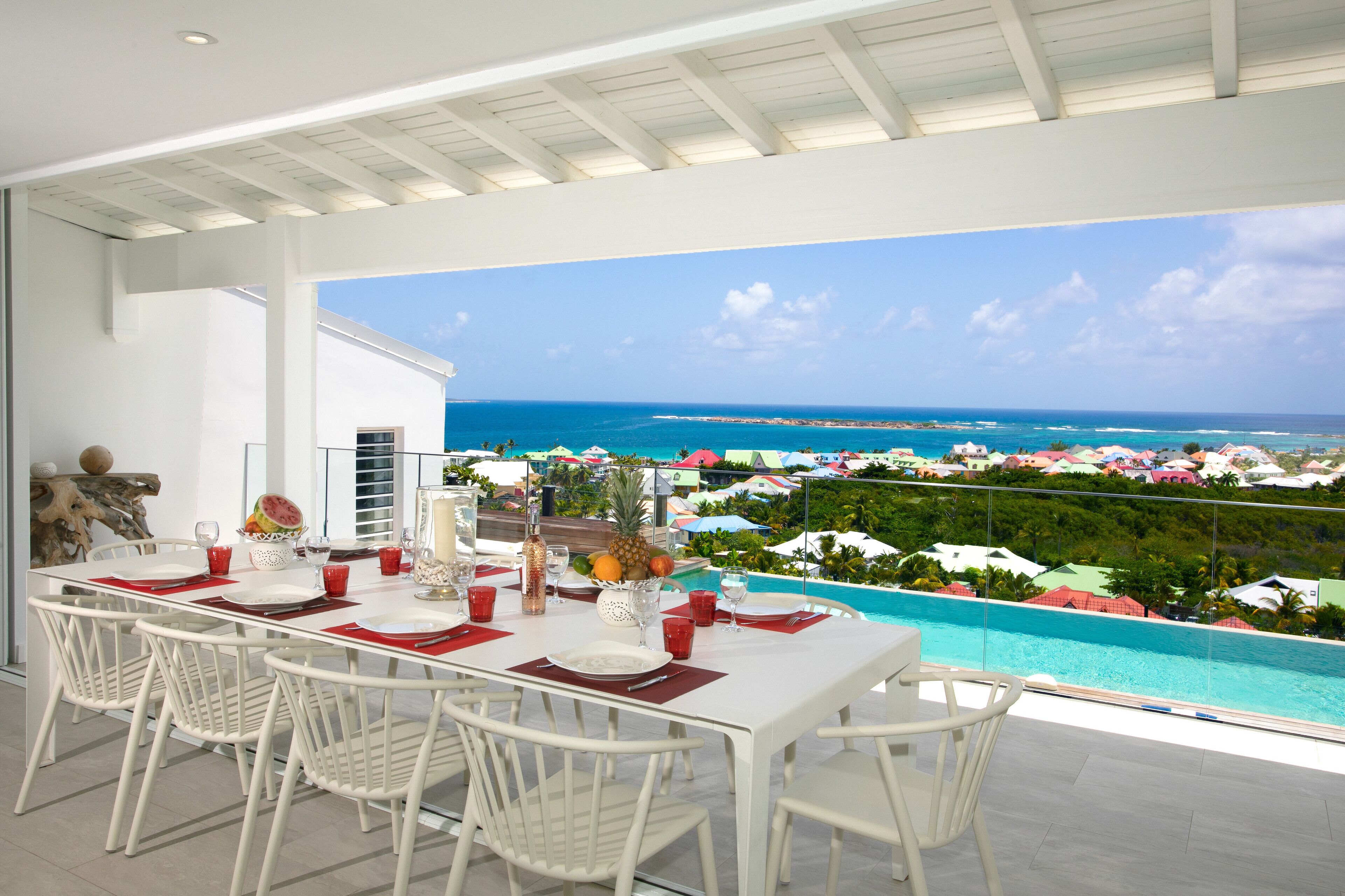 A dining area with a view of the ocean and a pool.