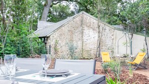 An outdoor dining area with a stone building in the background, surrounded by greenery. - House for 5 people - 500m from the beach (Noirmoutier-en-l´Ile)