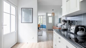 A modern kitchen with white cabinetry, a black countertop, and various appliances including a coffee maker and toaster. - House for 5 people - 500m from the beach (Noirmoutier-en-l´Ile)