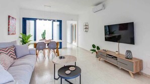 Un soggiorno moderno con divano, tavolino, televisione e zona pranzo con sedie e tavolo.