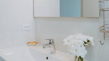 Ein modernes Badezimmer mit einem weißen Waschbecken, einem Spiegel und einem geometrisch gestalteten Leuchter.
