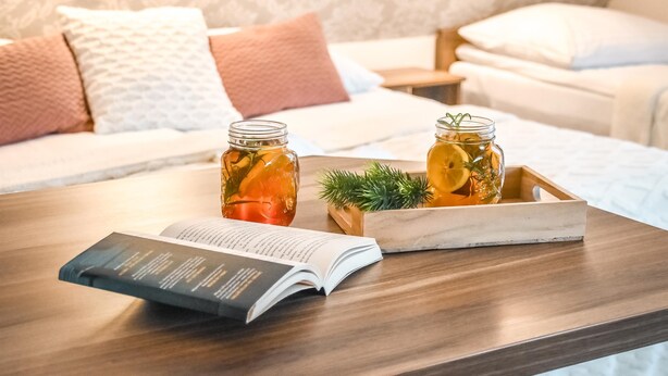 A wooden table with an open book, two glass jars with preserved lemons, and a wooden tray with a plant. - Słoneczny Dworek (Bukowina Tatrzanska)