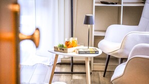A modern living room with a white sofa, a small table with a book and jars, and a lamp. - Słoneczny Dworek (Bukowina Tatrzanska)