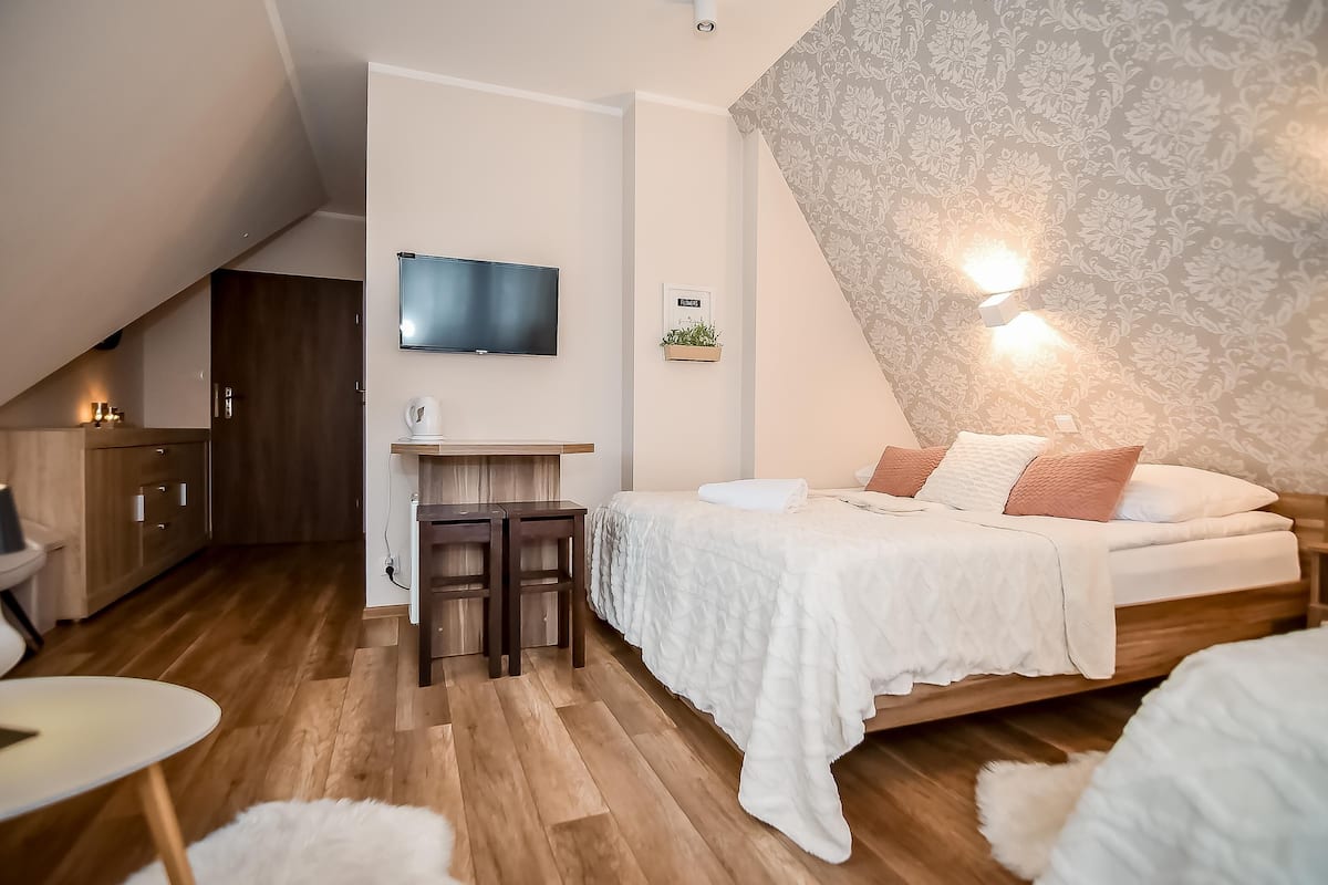 A modern bedroom with a bed, a desk, and a TV.