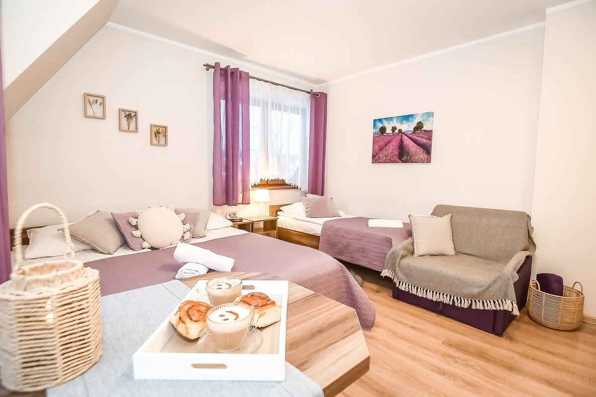 A cozy bedroom with a bed, two bedside tables, a dresser, a chair, and a breakfast tray.