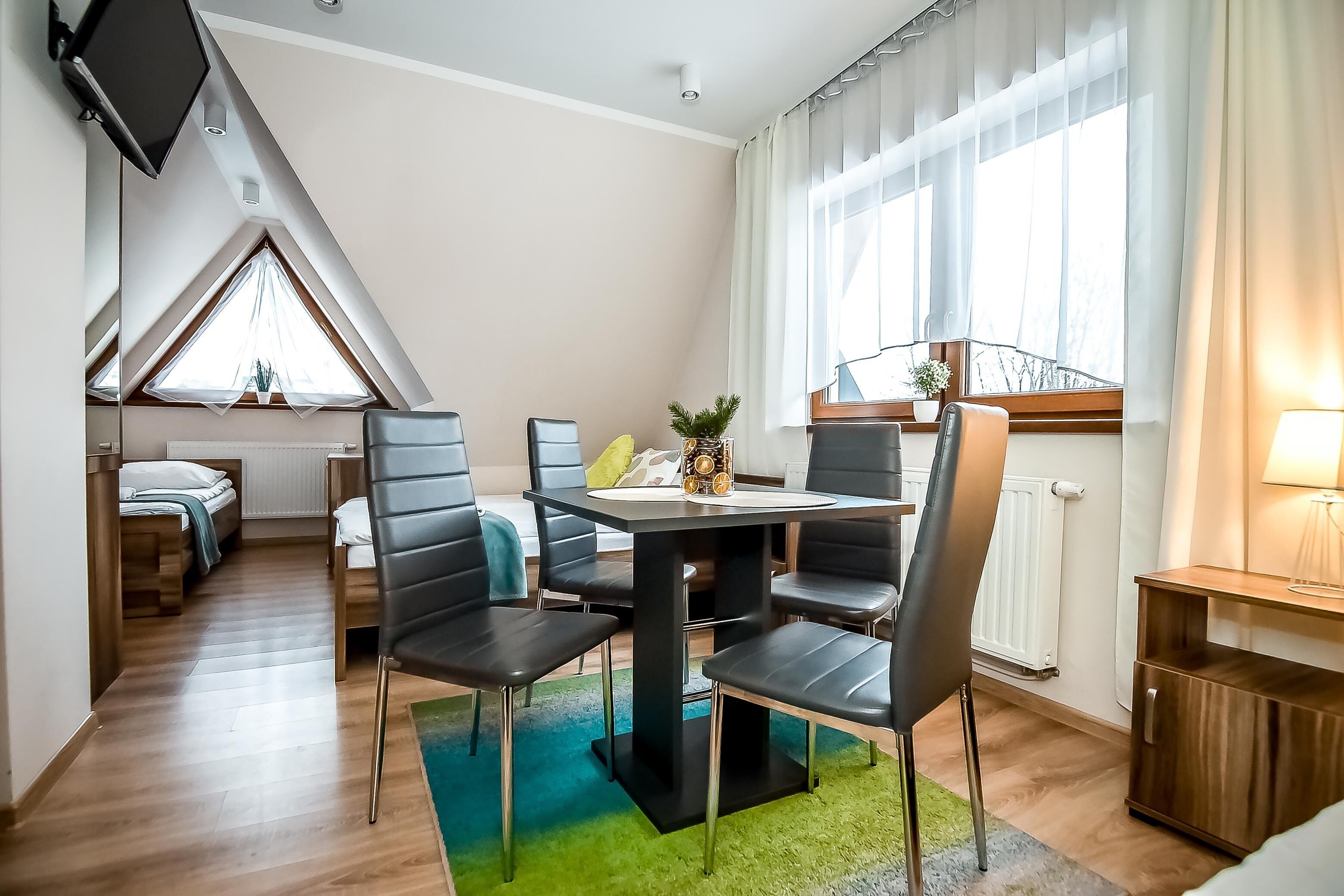 Une chambre d’hôtel moderne dotée d’un coin repas, d’un petit balcon et d’une grande fenêtre avec des rideaux.