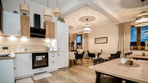 A modern kitchen with white cabinetry, a built-in oven, and pendant lighting. - Słoneczny Dworek (Bukowina Tatrzanska)
