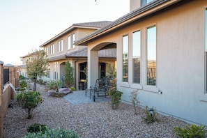 A residential building with a patio area, outdoor seating, and a gravel pathway.