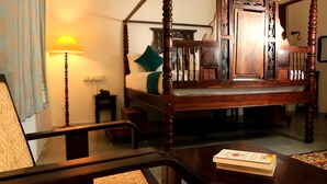 A traditional four-poster bed with a wooden headboard, a bedside table, a lamp, and a chair. - La Taara (Vanur)