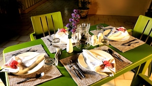 A table set for four with green chairs, a pitcher, candles, and a vase of flowers. - La Taara (Vanur)