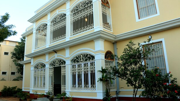 A two-story building with ornate white window railings and a balcony. - La Taara (Vanur)