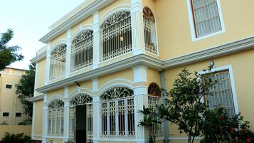 A two-story building with ornate white window railings and a balcony.