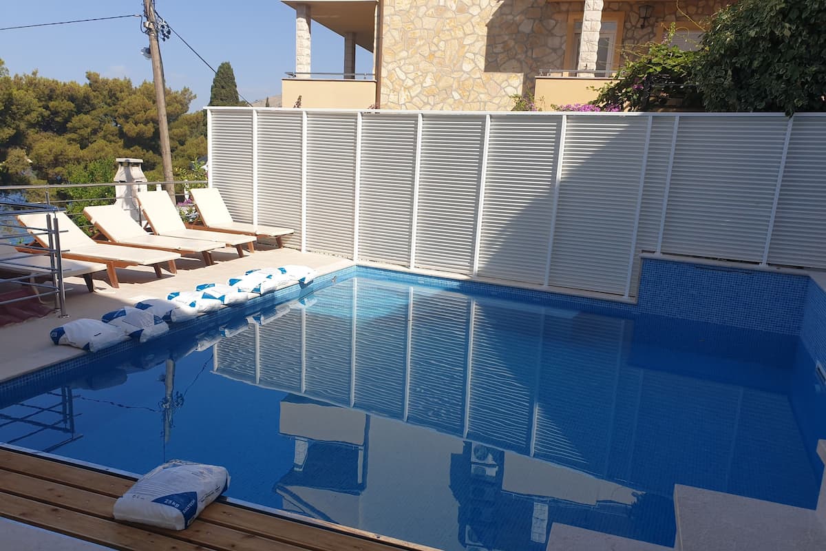 A swimming pool with lounge chairs and a stone building in the background.