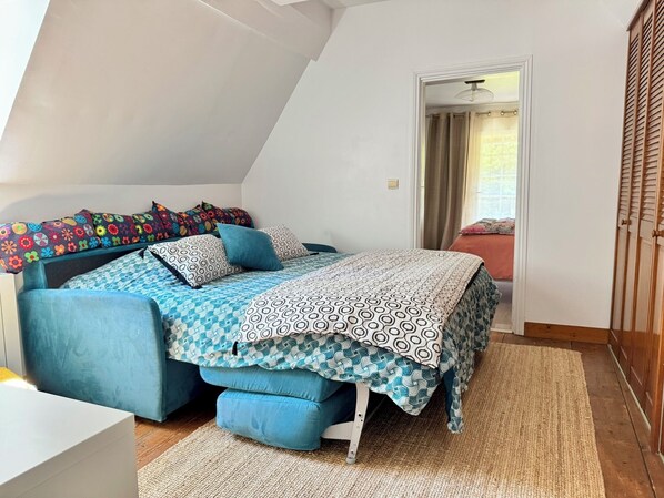 A bedroom with a loft bed, a small desk, and a walk-in closet.