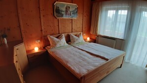Ett rum med träpanel på väggarna, en dubbelsäng, två sängbord med lampor, ett element och en tavla på väggen.