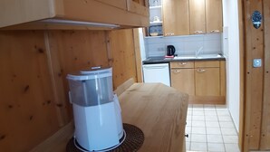 Ett kök med träinredning, en kaffebryggare på bänkskivan, skåp och en kakelbeklädd vägg bakom bänkskivan.