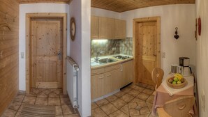 A compact kitchen with wooden cabinets, a sink, and a dining area with a table and chairs. - Ferienwohnung Apfelbaum 1. Etage, 42 qm, 1 Sep. Schlafzimmer, Balkon (Bad Feilnbach)