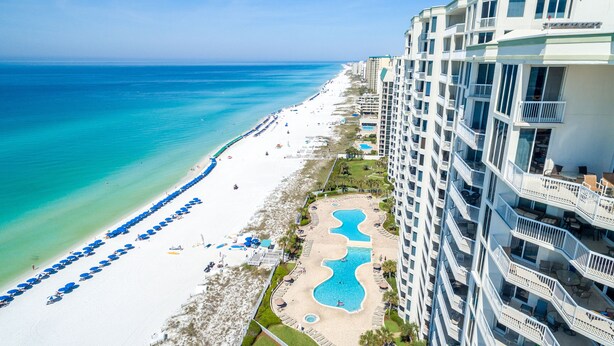 A beachfront hotel with a pool, beach umbrellas, and a view of the ocean. - Silver Beach Towers 1905e 3 Bedroom Condo by RedAwning (Destin)