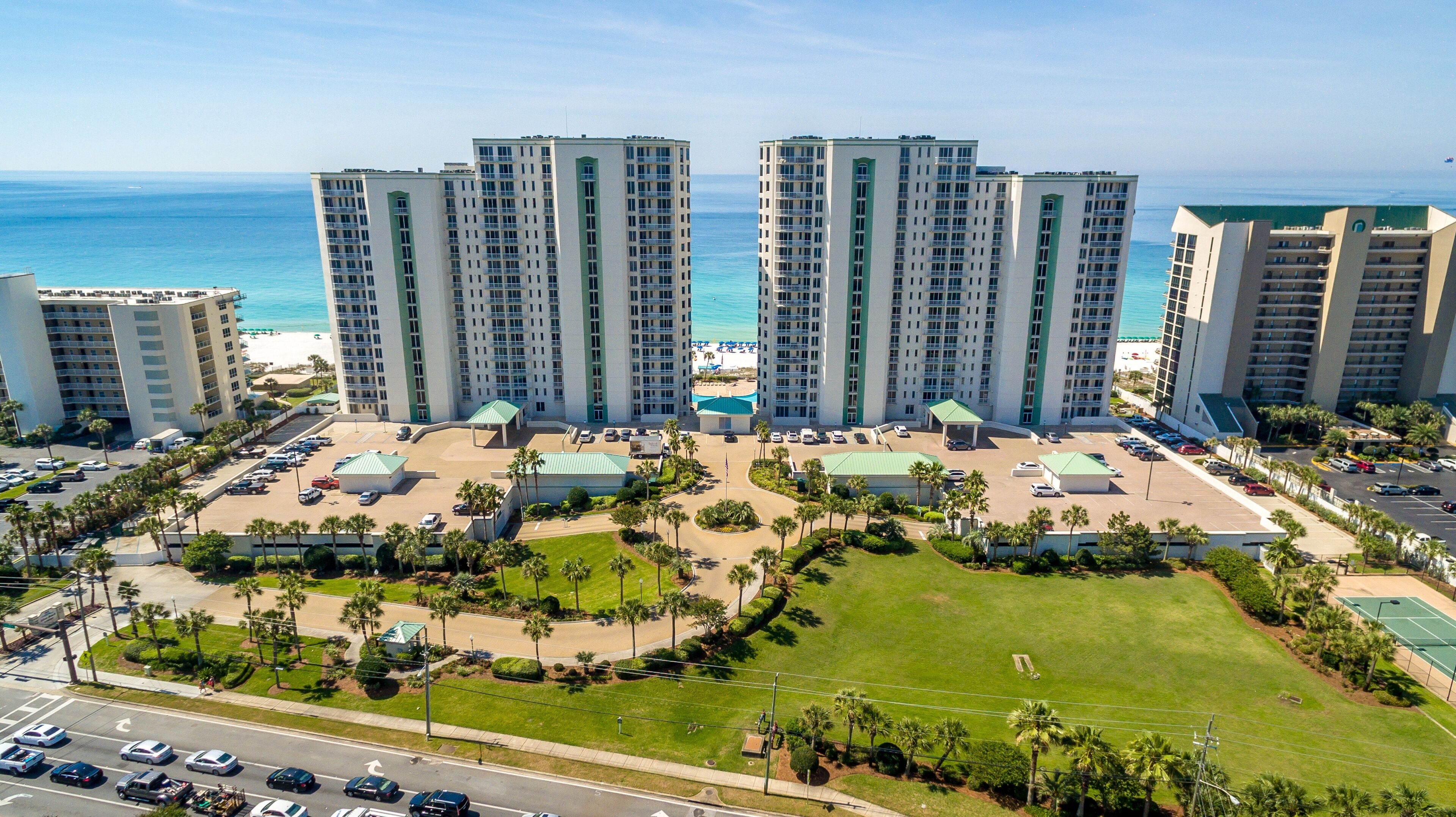 A high-rise hotel with multiple floors, a central courtyard, and a view of the ocean.