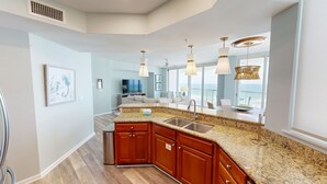 Una cocina moderna con encimeras de granito, armarios de madera y un lavamanos de acero inoxidable.