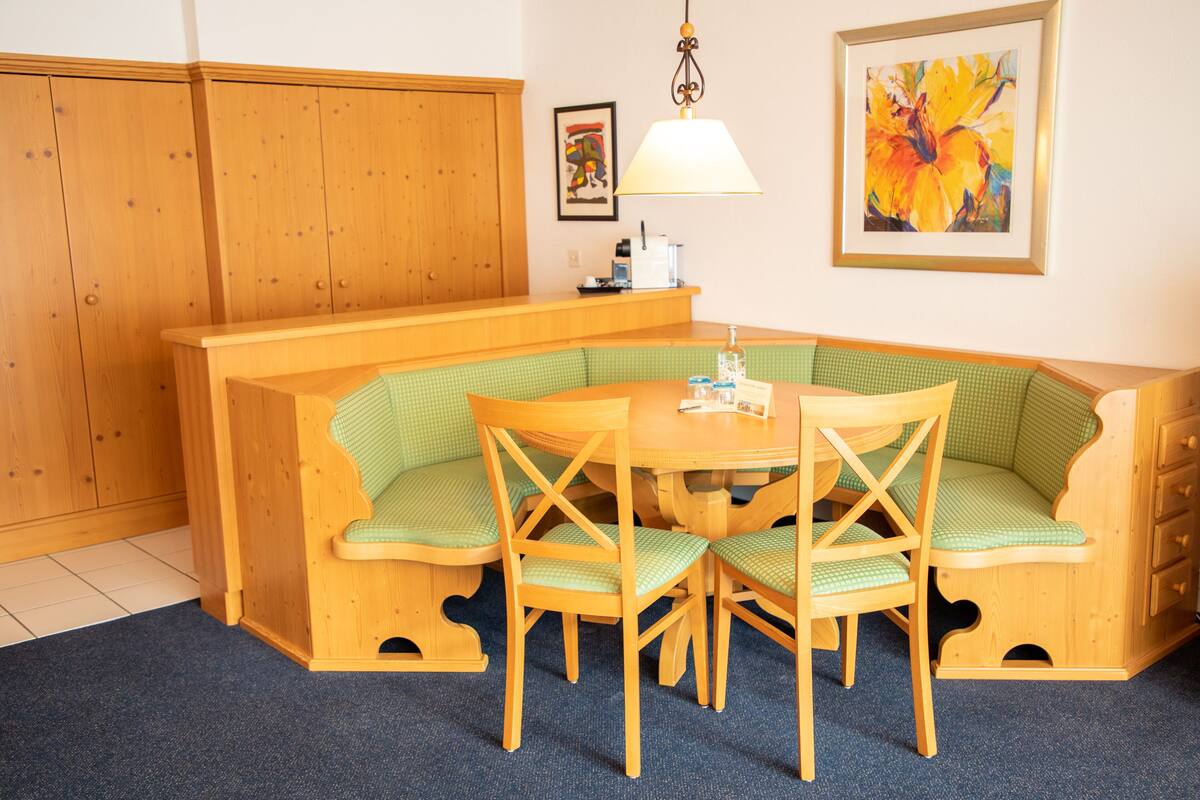 Een gezellige kamer met een zithoek met een houten bank, een ronde tafel en een lamp.