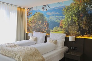 Une chambre d’hôtel avec un grand lit, deux tables de chevet, une petite table et une lampe fixée au mur.
