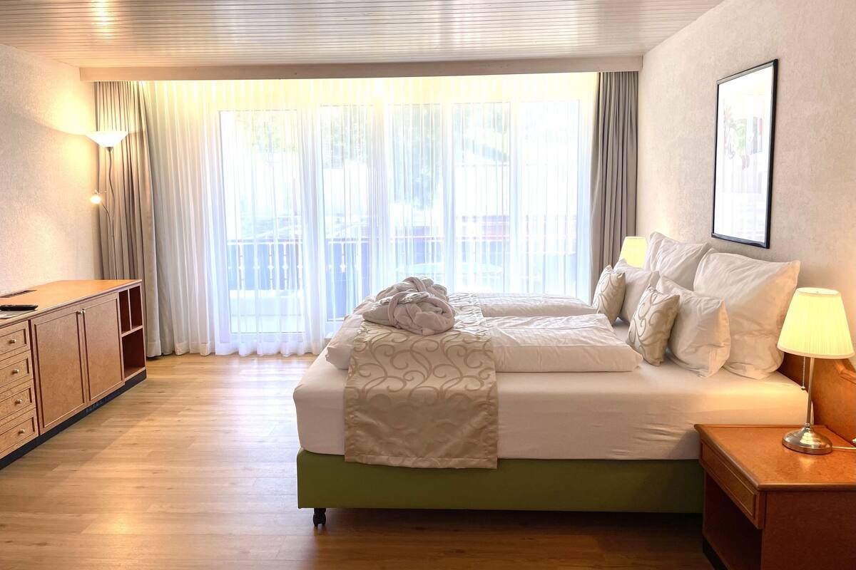Een hotelkamer met een bed, bureau, lamp en raam met gordijnen.