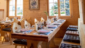 A wooden dining area with a long table set for a meal, surrounded by cushioned benches. - Alpenlodge Val Gronda (Obersaxen)