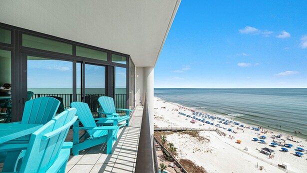 A balcony with turquoise Adirondack chairs overlooking a beach with umbrellas and people. - New to the Rental Market, New Owner, Beachfront!! (Orange Beach)