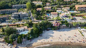 Vue aérienne d’un quartier résidentiel situé sur la côte, avec de nombreux immeubles, une plage et une piscine.