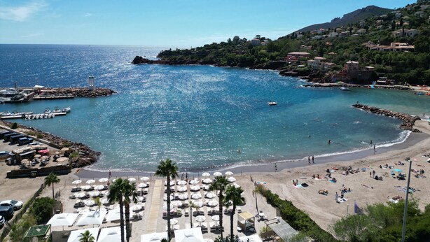 A coastal beach area with a marina, beach umbrellas, and a rocky coastline. - Villa La Cigalette-Gaia's Villas,Beachside Estate with Pool-Steps from the Beach (Théoule-sur-Mer)
