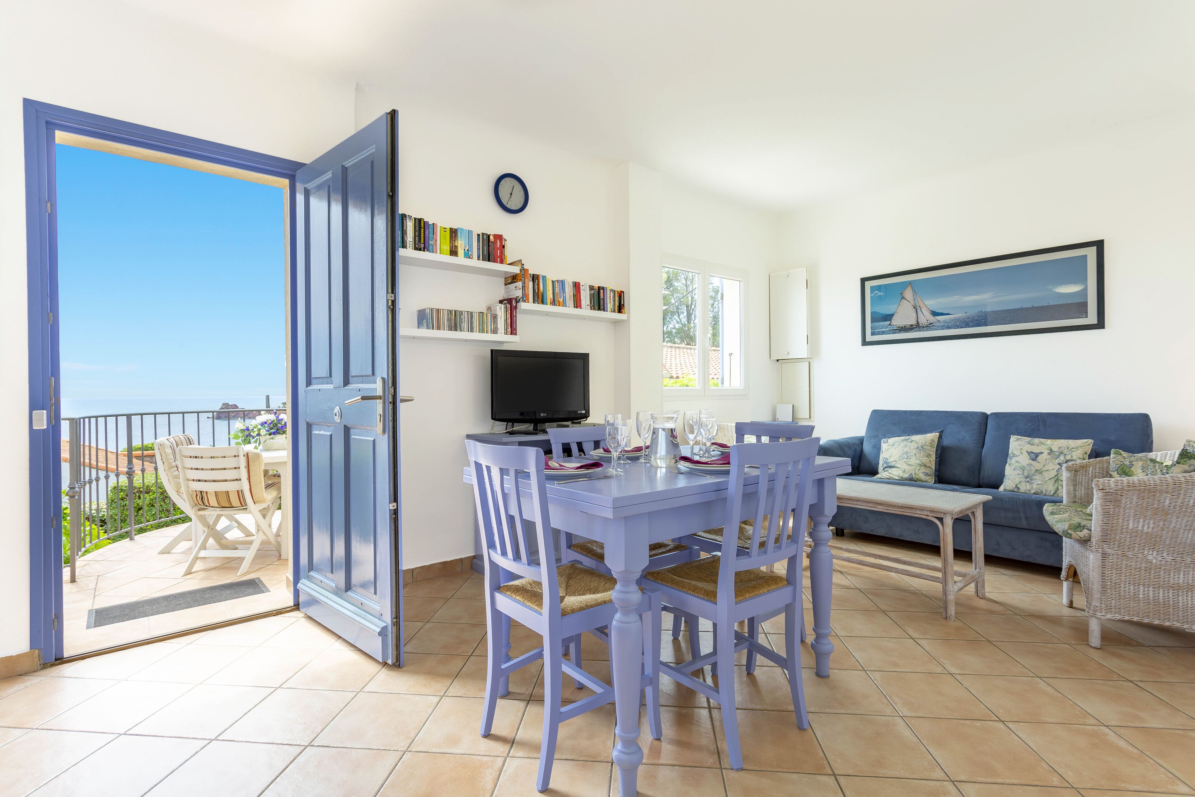 A dining area with a table set for four, a television, and a bookshelf with books.