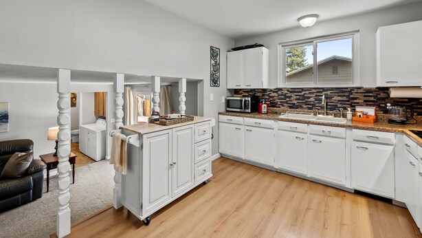 A modern kitchen with white cabinets, a microwave, and a large window. - Charming Arvada Home - Walking distance to Olde Town (Arvada)