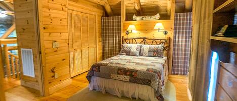 Un dormitorio rústico de cabaña con una cama, dos lámparas fijadas a la pared y una cortina escocesa.