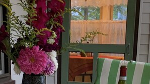 A table with a bottle of wine, a vase of flowers, and a tablecloth with a floral pattern. - Beautiful Yr Round Cottage Great Porch, Heart of MTG, Near Hershey, Lititz, Lanc (Mount Gretna)