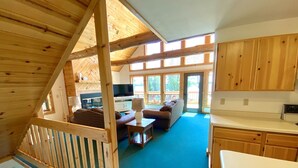 L’intérieur d’un chalet en bois comprend un espace de vie, une cuisine et un balcon doté de grandes fenêtres.