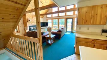 L’intérieur d’un chalet en bois comprend un espace de vie, une cuisine et un balcon doté de grandes fenêtres.