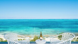 A balcony with two white wicker chairs facing a turquoise sea under a clear sky. - Bella Horizonte - Beachfront 7 (Savaneta)