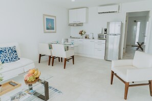 A modern kitchen with white cabinets, a refrigerator, and a dining area with a table and chairs. - Bella Horizonte - Beachfront 8 (Savaneta)