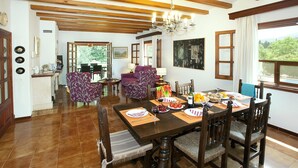 A dining area with a wooden table set for four, surrounded by chairs, with a view of greenery outside. - ROTGER. In Pollensa, just 800 m from the town centre! (Pollensa)