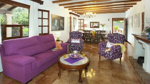 A living room with a purple sofa, patterned armchairs, a wooden coffee table, and a dining area in the background. - ROTGER. In Pollensa, just 800 m from the town centre! (Pollensa)