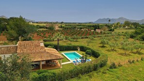 A villa with a tiled roof, a swimming pool, and a view of the surrounding countryside and mountains. - GERANIOS. Relax and enjoy! (Puerto Pollensa)