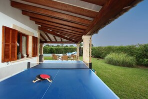 An outdoor ping pong table under a wooden pergola with a view of a pool and garden. - GERANIOS. Relax and enjoy! (Puerto Pollensa)