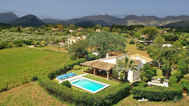 A villa with a swimming pool, surrounded by lush greenery and mountains in the background. - GERANIOS. Relax and enjoy! (Puerto Pollensa)