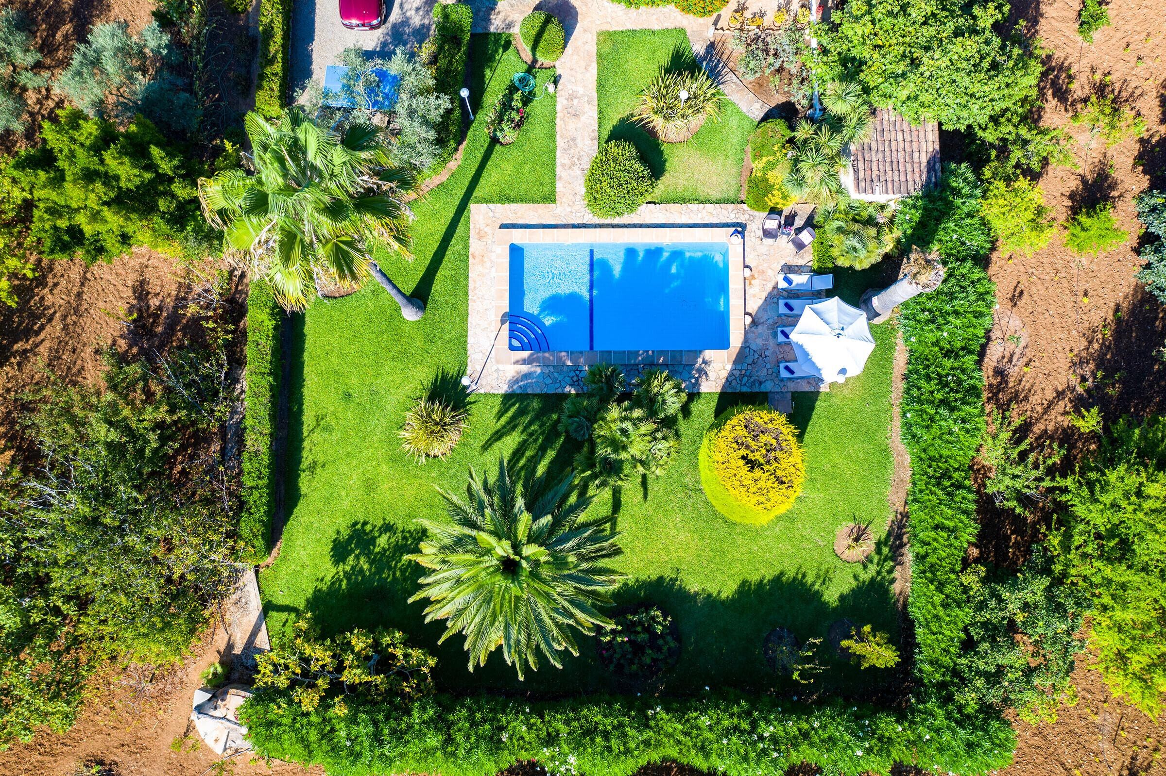 Vista aèria d'una propietat amb piscina, envoltada de gespes cuidades i diversos arbres.