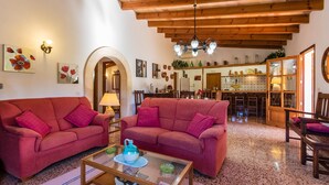 A cozy living room with two red sofas, a glass coffee table, and a wooden ceiling. - MORENO. Fabulous garden, memorable holidays (Pollensa)