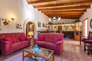 A cozy living room with two red sofas, a glass coffee table, and a wooden ceiling.