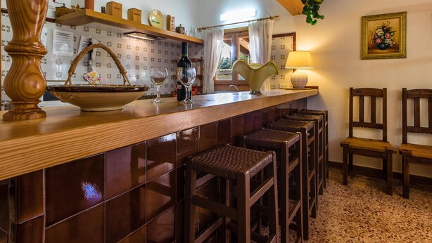 A kitchen with a wooden bar, stools, and a window with curtains. - MORENO. Fabulous garden, memorable holidays (Pollensa)