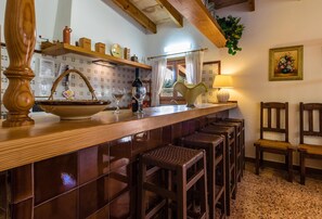 A kitchen with a wooden bar, stools, and a window with curtains.